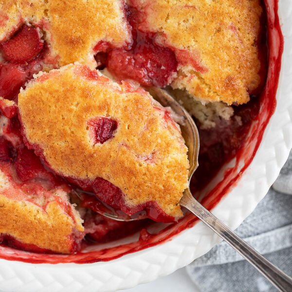 Strawberry rhubarb pudding cake being spooned out.