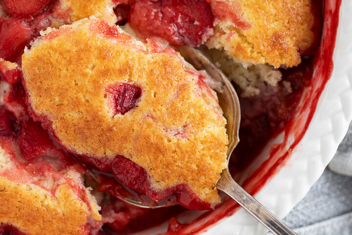 Strawberry rhubarb pudding cake being spooned out.