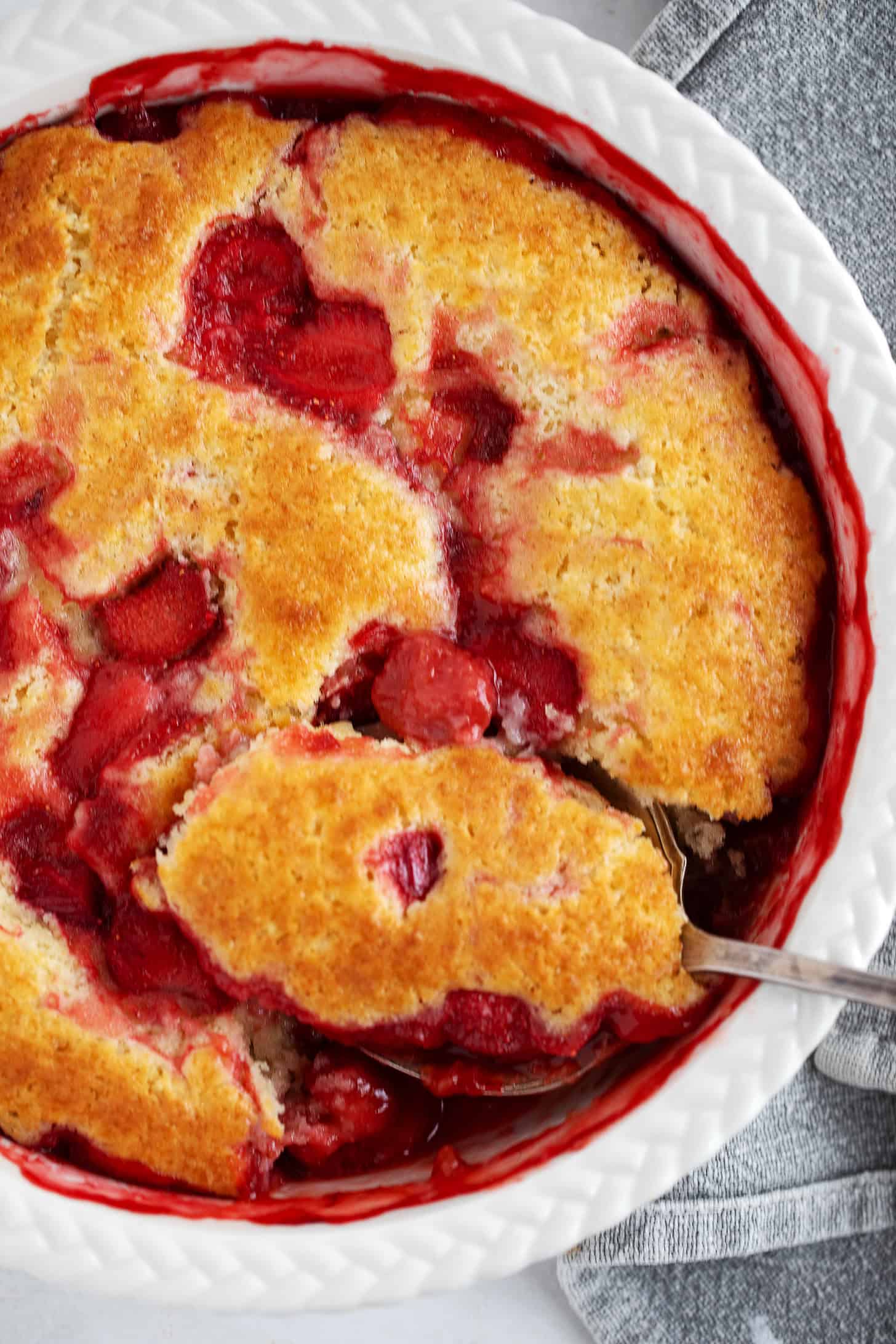 Strawberry rhubarb pudding cake being spooned out.