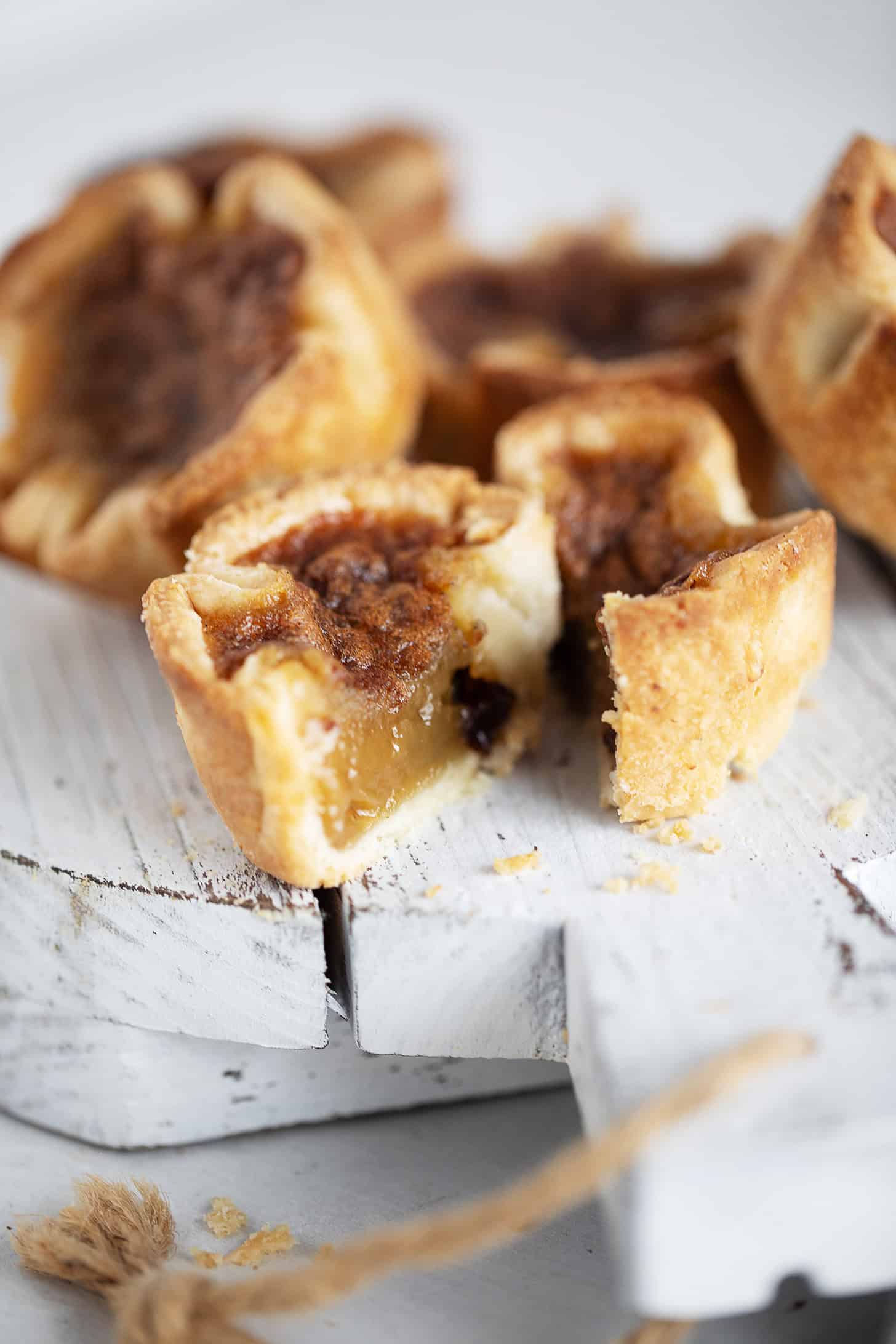 Butter tarts on a serving board with one tart sliced in half.