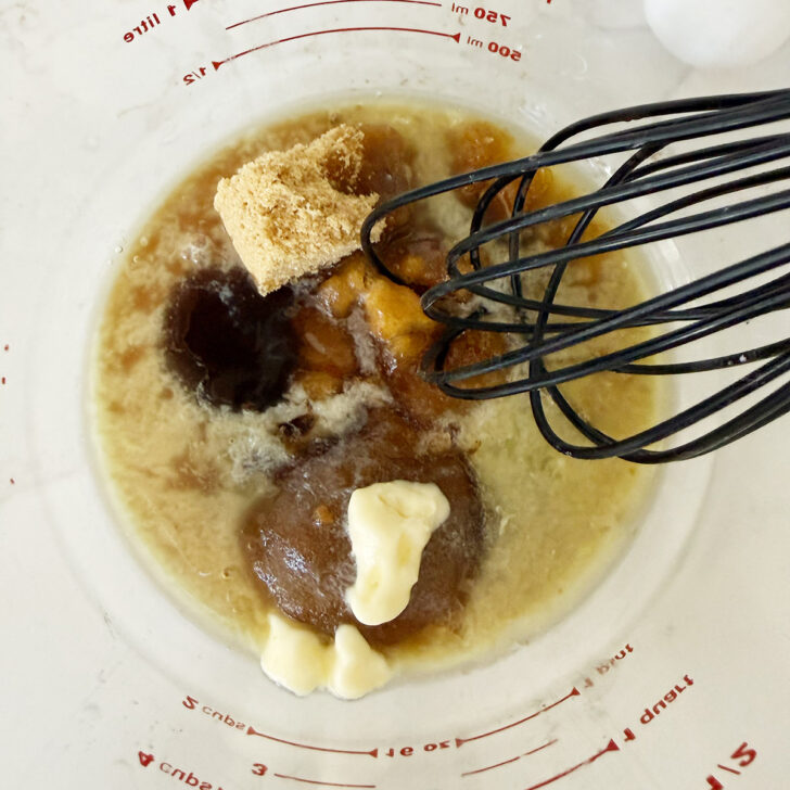Butter tart filling ingredients in a bowl with a whisk.