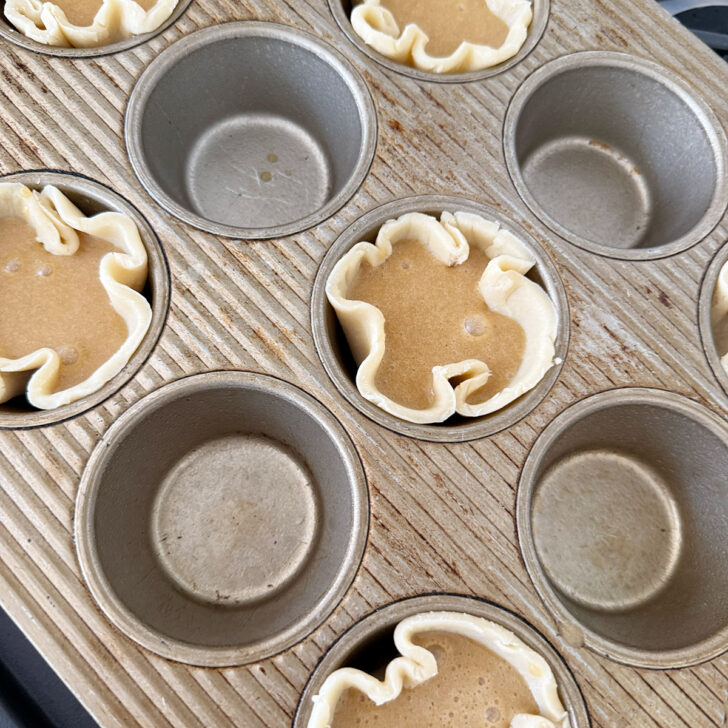 Butter tart filling poured into the tart shells.