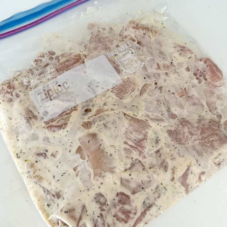 Chicken breast pieces added to the souvlaki marinade in a plastic zipper bag.