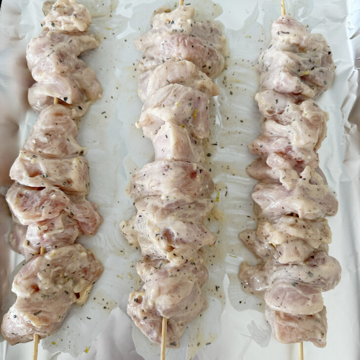 Souvlaki-marinated chicken breast pieces threaded onto skewers.
