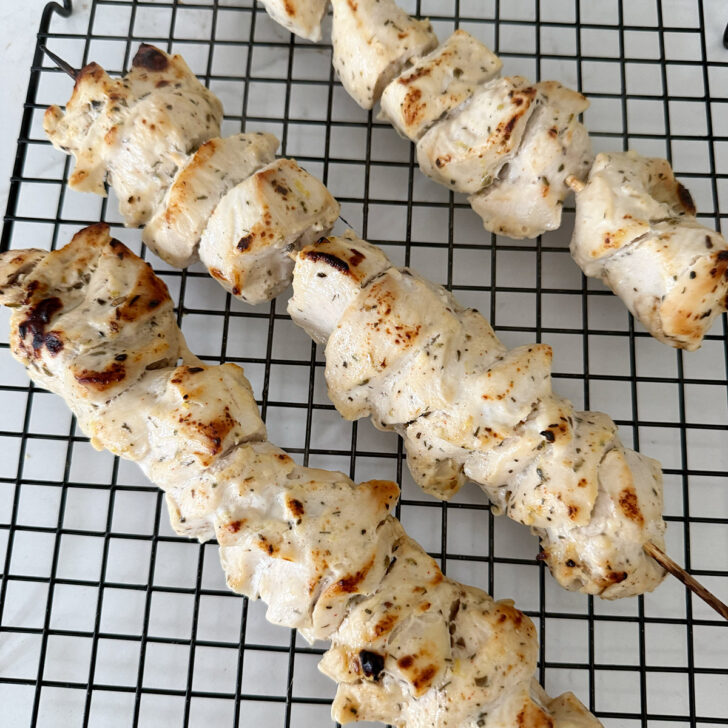 Chicken souvlaki skewers on a cooling rack after cooking.