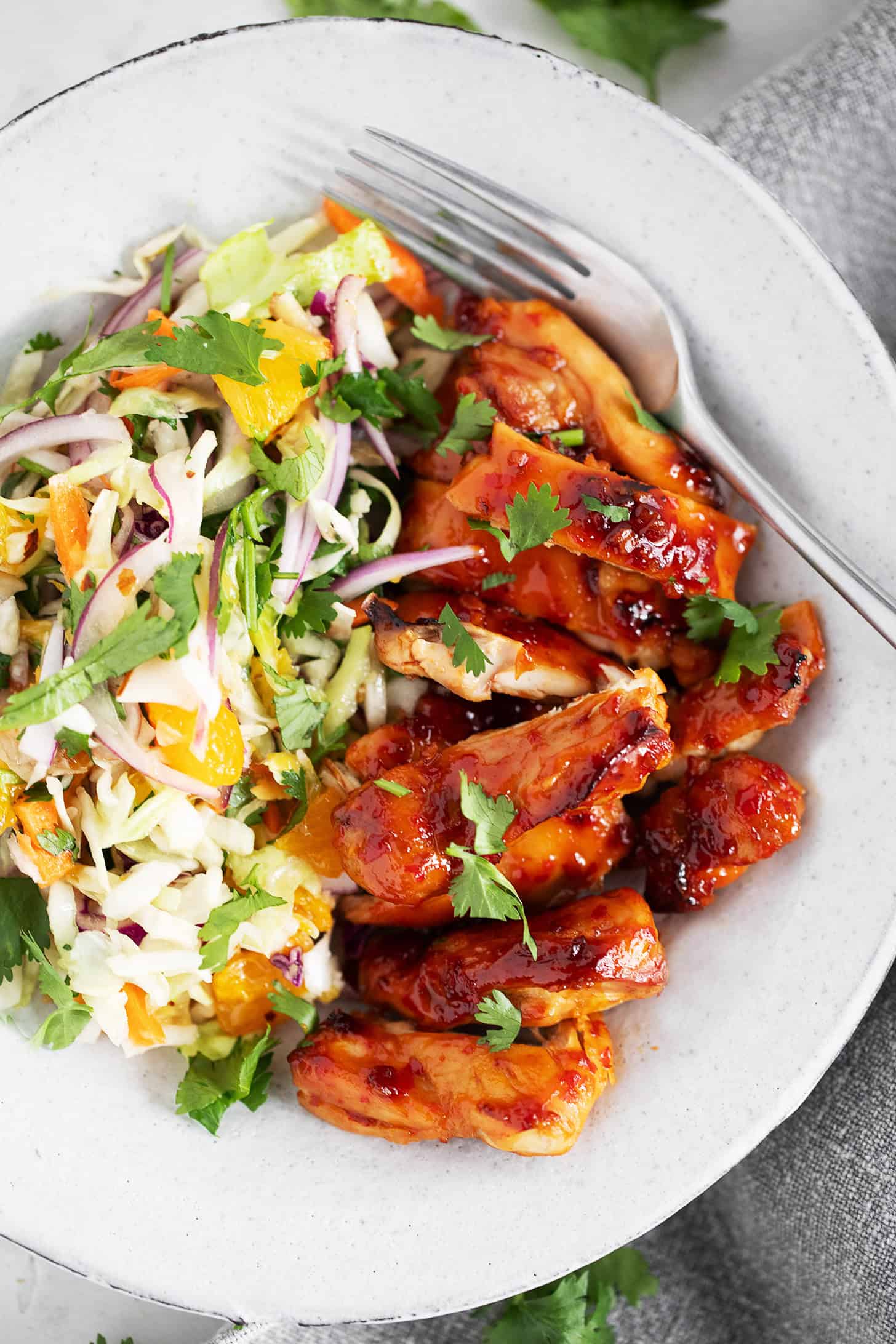 Hot honey chicken thighs with citrus slaw on a dinner plate.