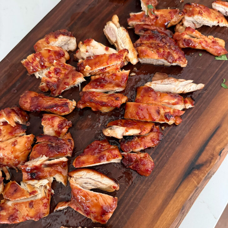 Cooked hot honey chicken sliced on a cutting board.