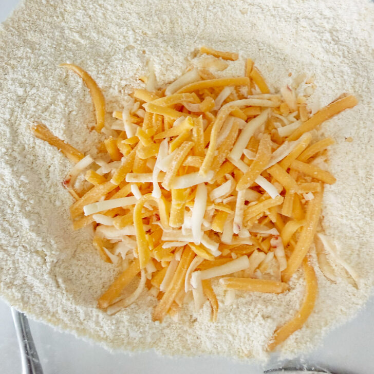 Shredded cheddar cheese added to the dry ingredients.