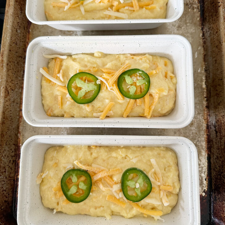 Batter spooned into mini loaf pans and topped with cheddar and jalapeños.
