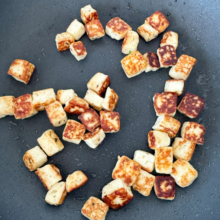 Browned halloumi cheese in a skillet.