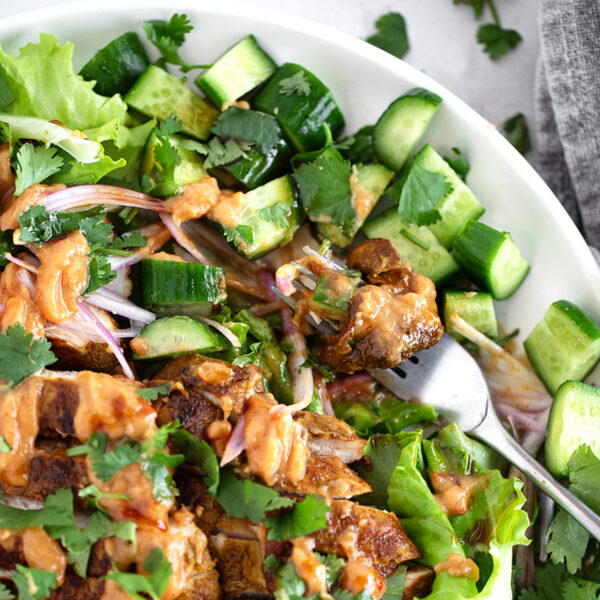 Peanut chicken salad plated with lime wedges.