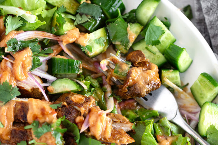 Peanut chicken salad plated with lime wedges.