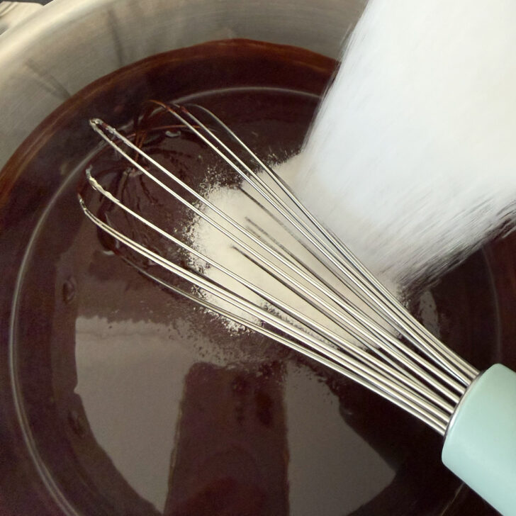 Adding white sugar to the melted chocolate and butter.