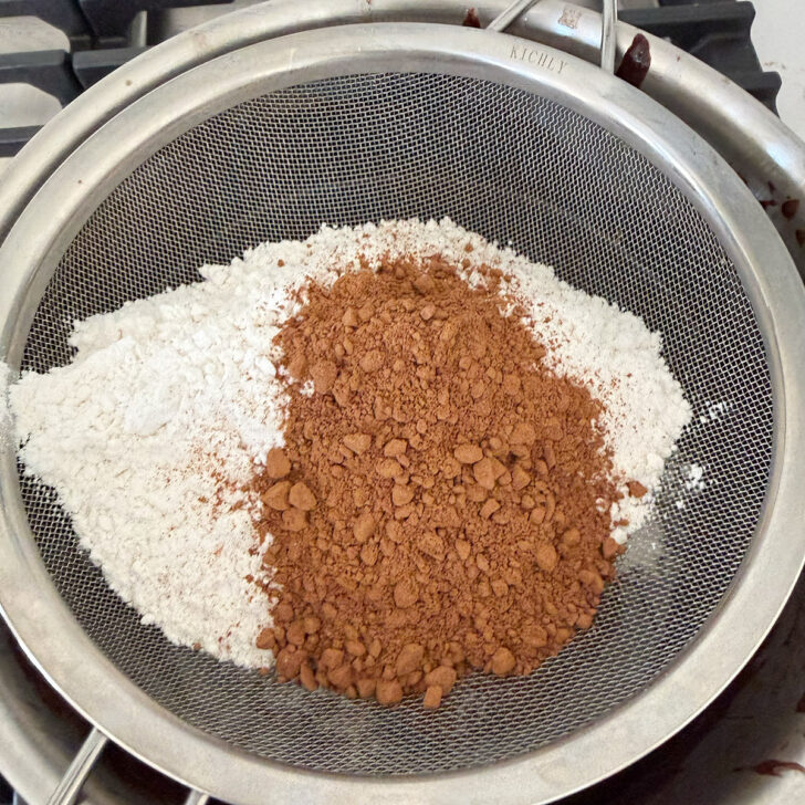 Sifting the flour and cocoa powder into the brownie batter.