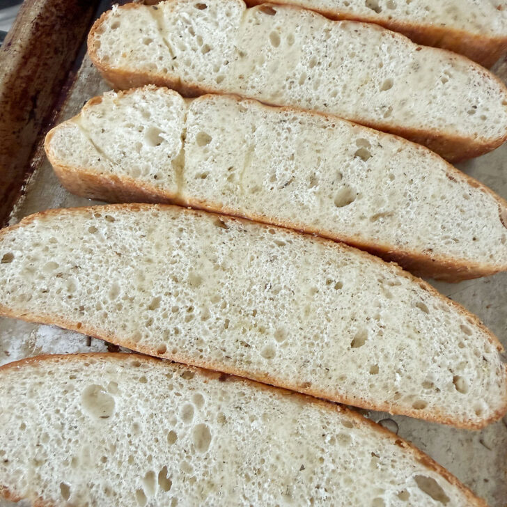 Focaccia slices drizzled with olive oil before toasting.