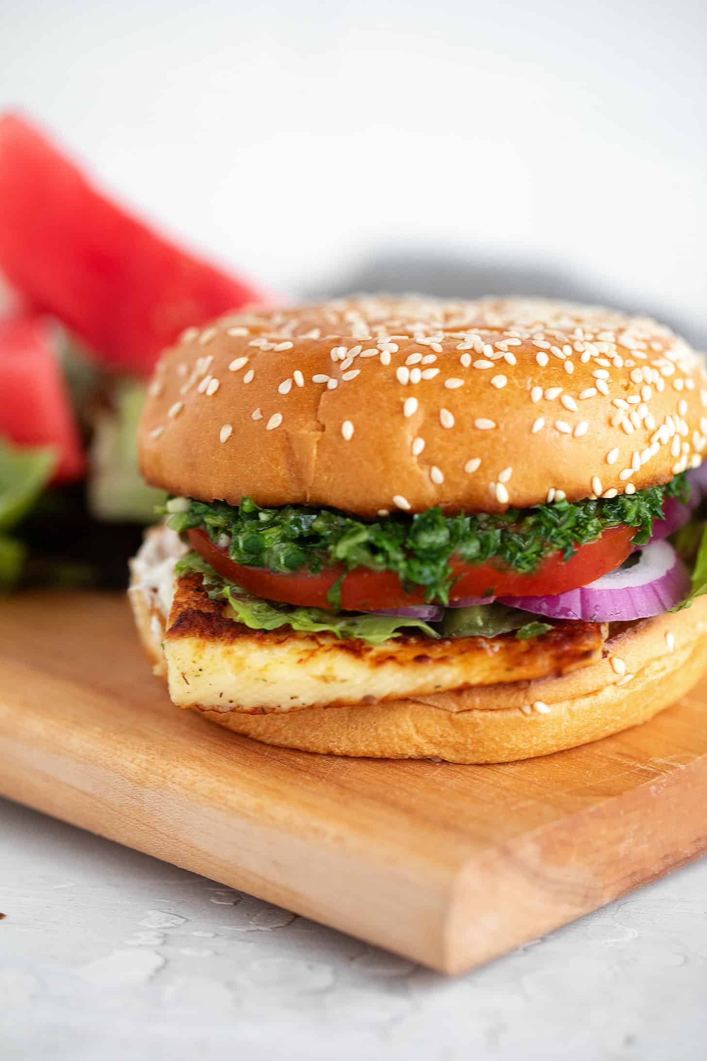 Halloumi burger on a serving board with watermelon slices.