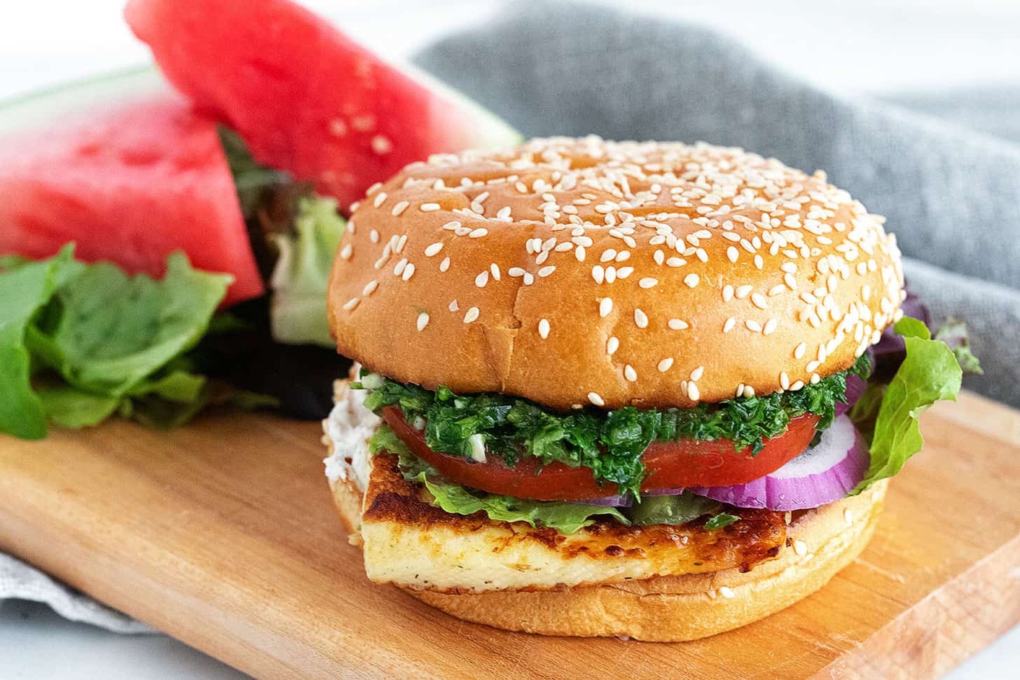 Halloumi burger on a serving board with watermelon.