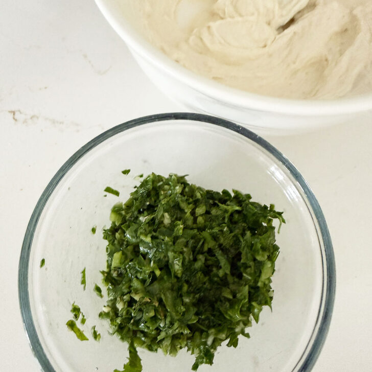 Prepared zhug and tahini yogurt sauce in bowls.