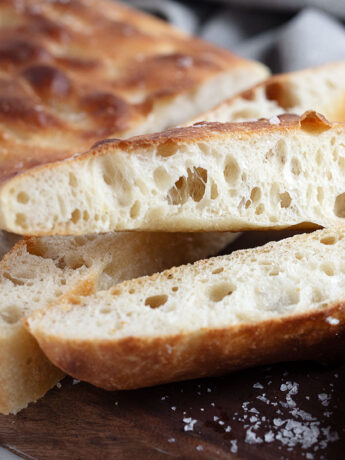 Overnight rise focaccia sliced on a cutting board.