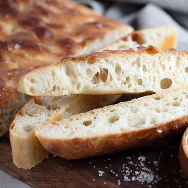 Overnight rise focaccia sliced on a cutting board.