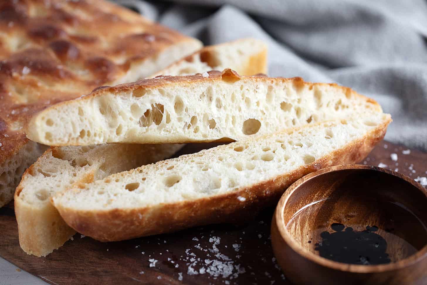 Overnight rise focaccia sliced on a cutting board.