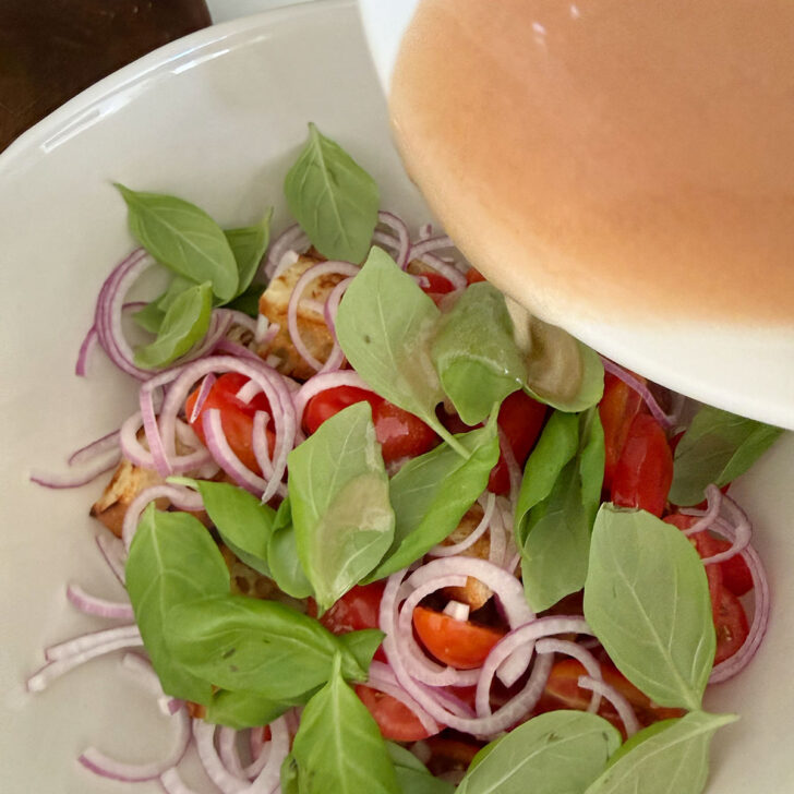 Pouring the vinaigrette over the salad.
