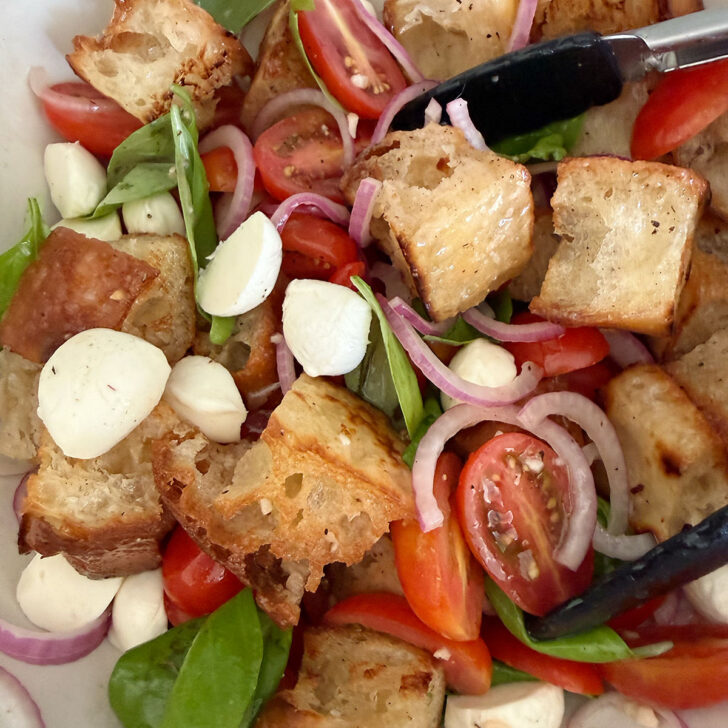 Tossing the focaccia panzanella salad in a bowl.
