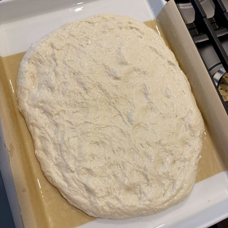 Refrigerated focaccia dough added to the prepared baking pan.