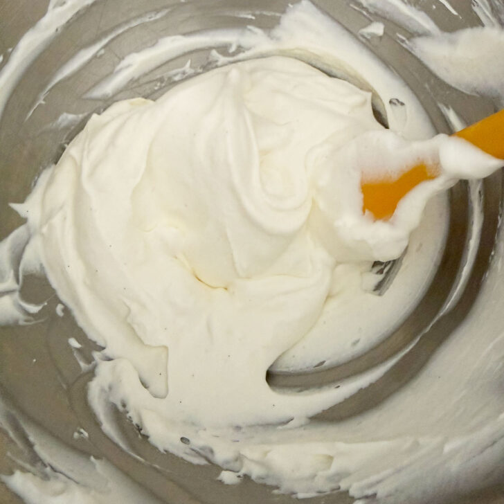 Folding the whipped cream into the cream cheese mixture.