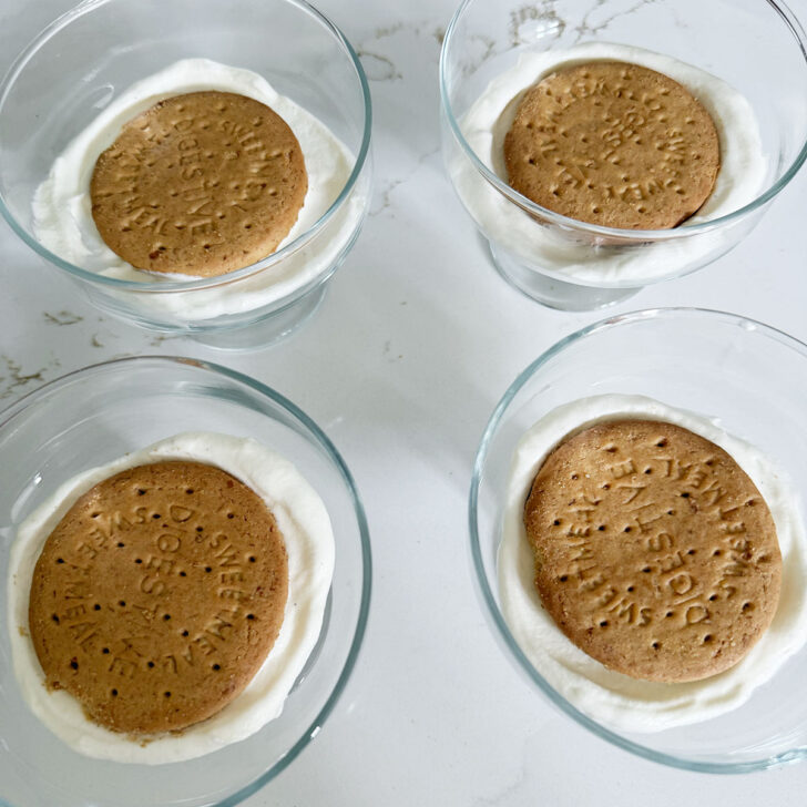 Filling dessert cups with the cream mixture and a Digestive cookie.