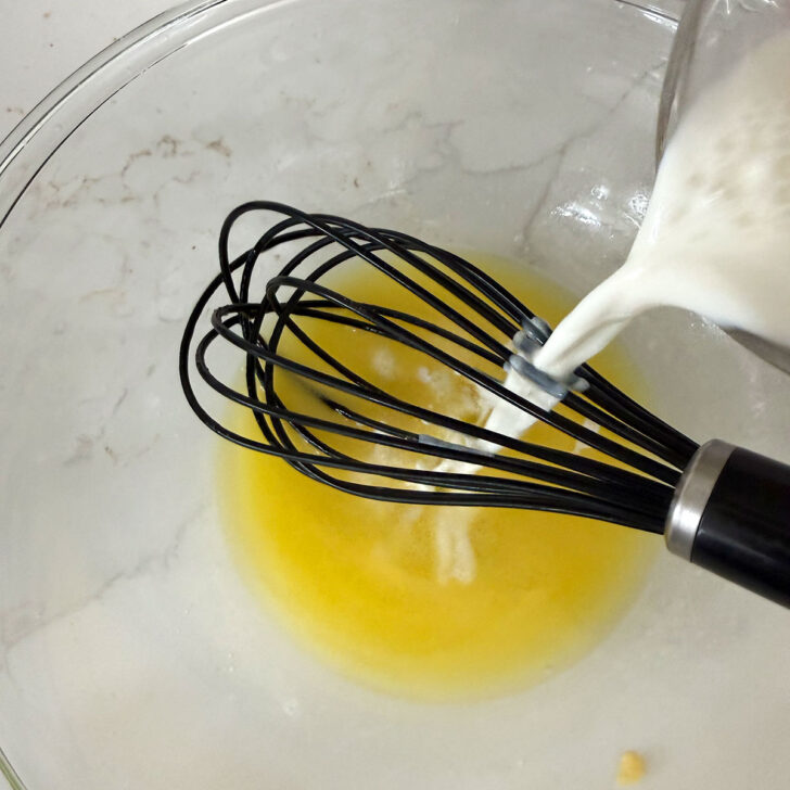 Adding milk to melted butter in a bowl.
