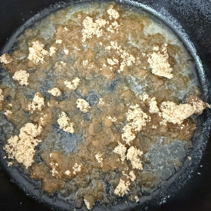 Brown sugar added to melted butter in a cast iron skillet.