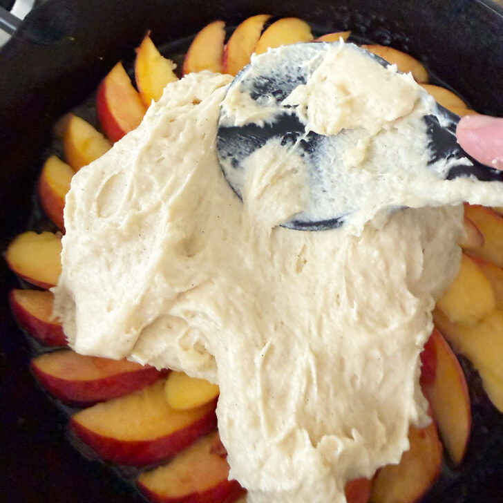 Spreading the cake batter over the sliced peaches.