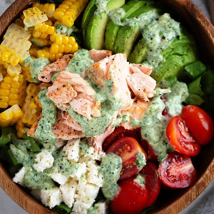 Cilantro lime salmon salad with corn, feta and cherry tomatoes in a wooden salad bowl.
