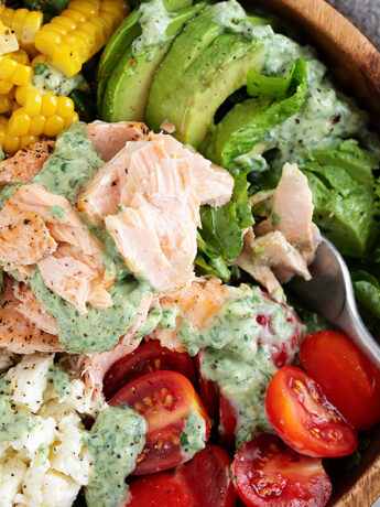Cilantro lime salmon salad with corn, feta and cherry tomatoes in a wooden salad bowl.