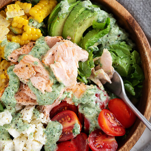 Cilantro lime salmon salad with corn, feta and cherry tomatoes in a wooden salad bowl.