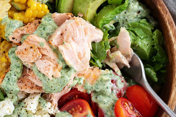 Cilantro lime salmon salad with corn, feta and cherry tomatoes in a wooden salad bowl.