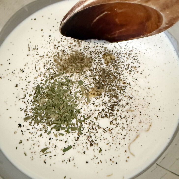 Cream, garlic, mustard and herbs added to a saucepan to heat.