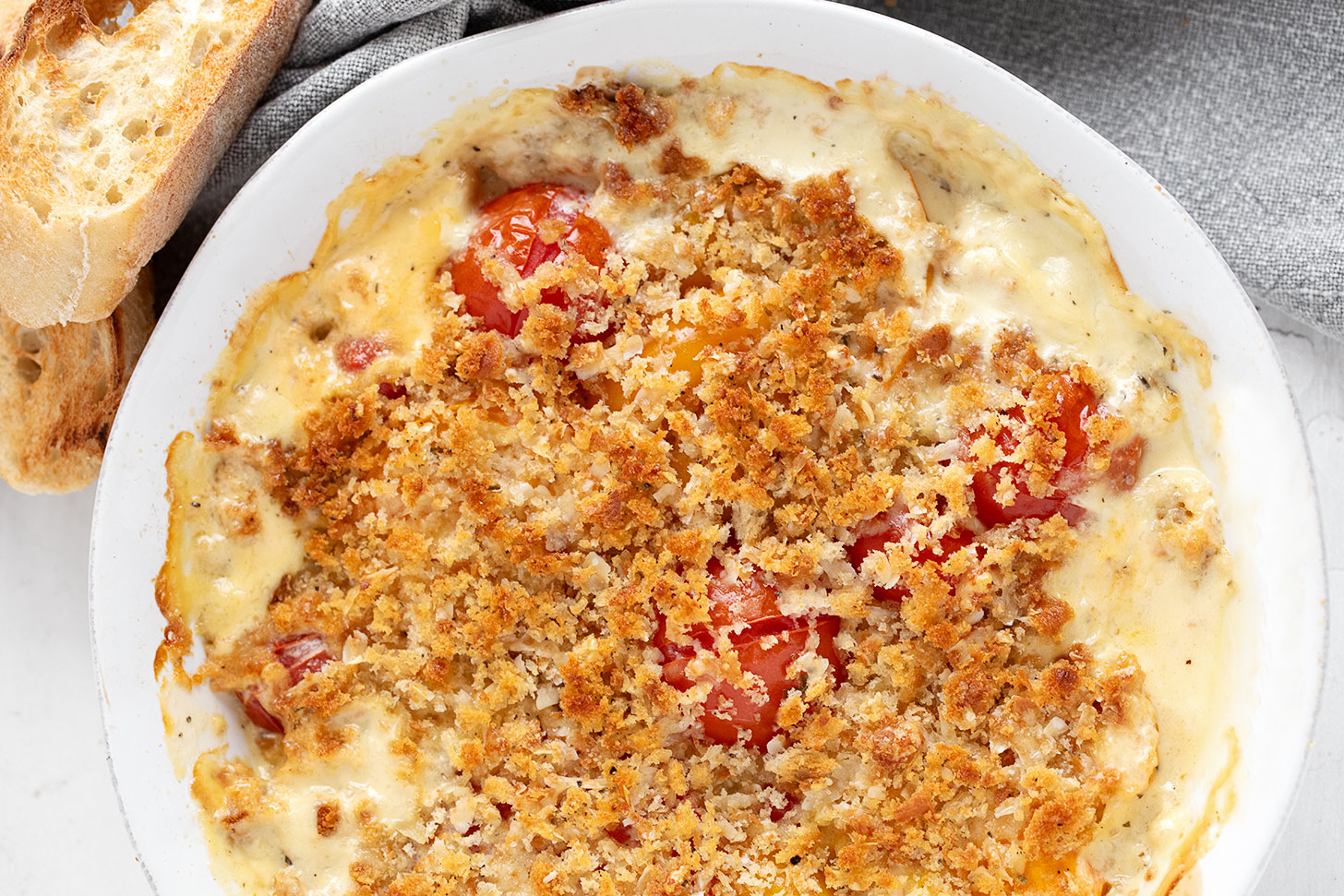 Tomato gratin in the baking dish with toasted bread slices on the side.