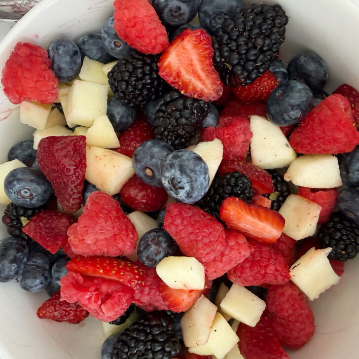 Fresh strawberries, raspberries, blackberries, blueberries and apples in a bowl.