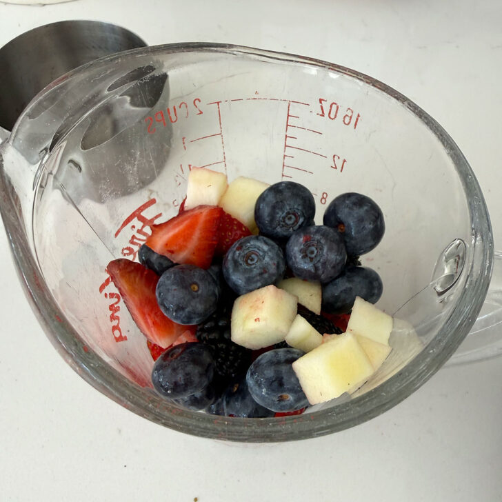 A portion of the fresh fruit removed from the bowl to a measuring cup.
