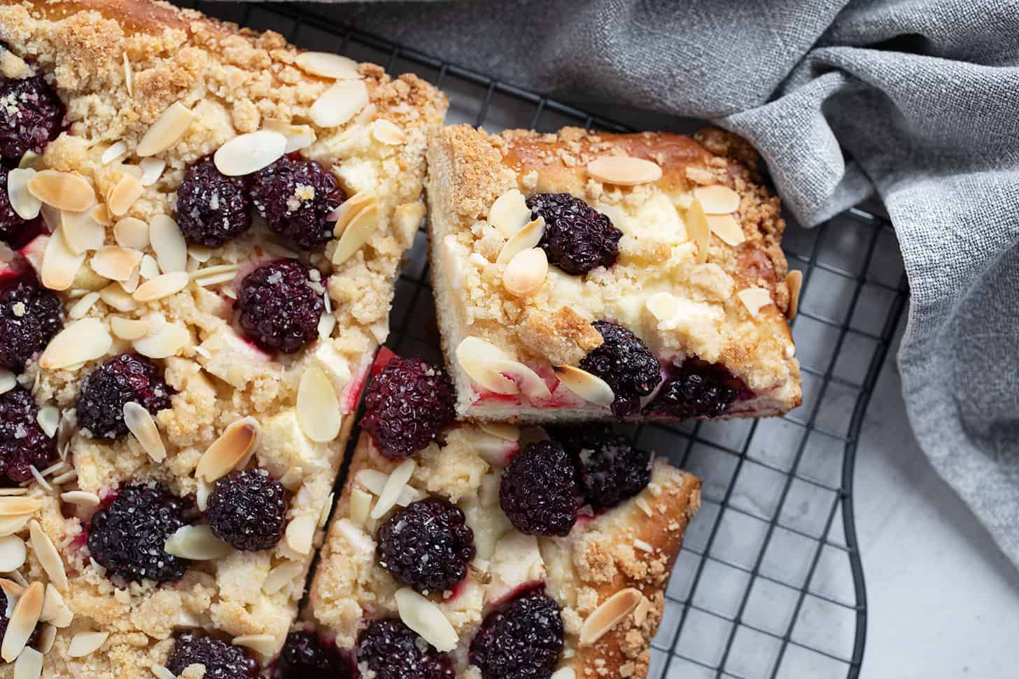 Blackberry apple kuchen sliced on a wire rack.