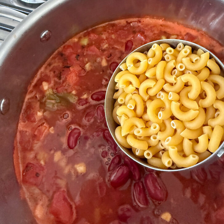 Adding the elbow macaroni to the pot.