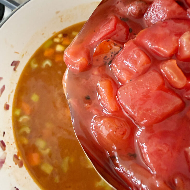 Adding the canned diced tomatoes to the pot,