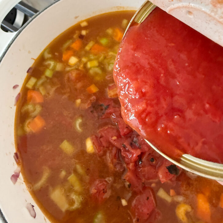 Adding the canned crushed tomatoes to the pot.