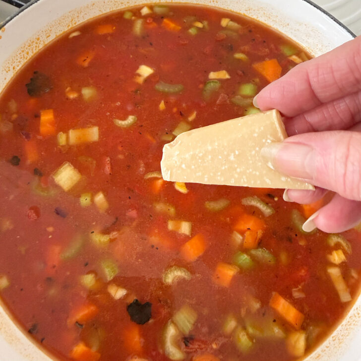 Adding the parmesan rind to the minestrone.