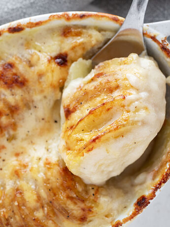 Potato gratin in the baking dish with some spooned out.