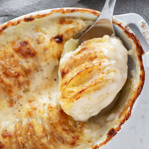 Potato gratin in the baking dish with some spooned out.