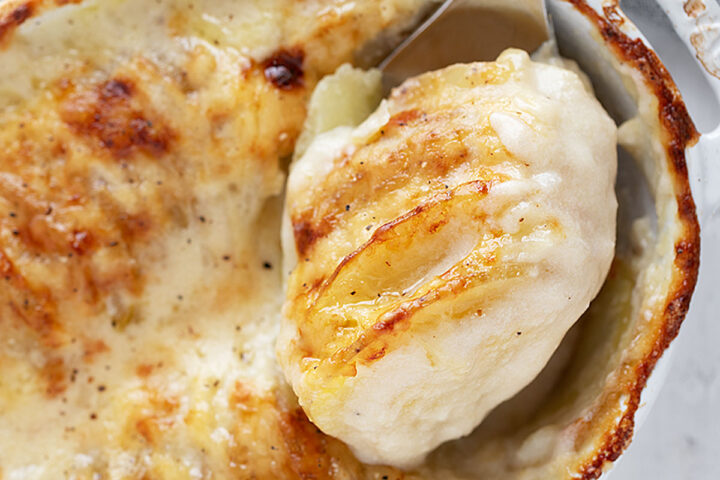 Potato gratin in the baking dish with some spooned out.