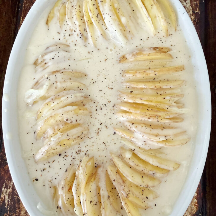 Cheese sauce poured over the sliced potatoes in the casserole dish.